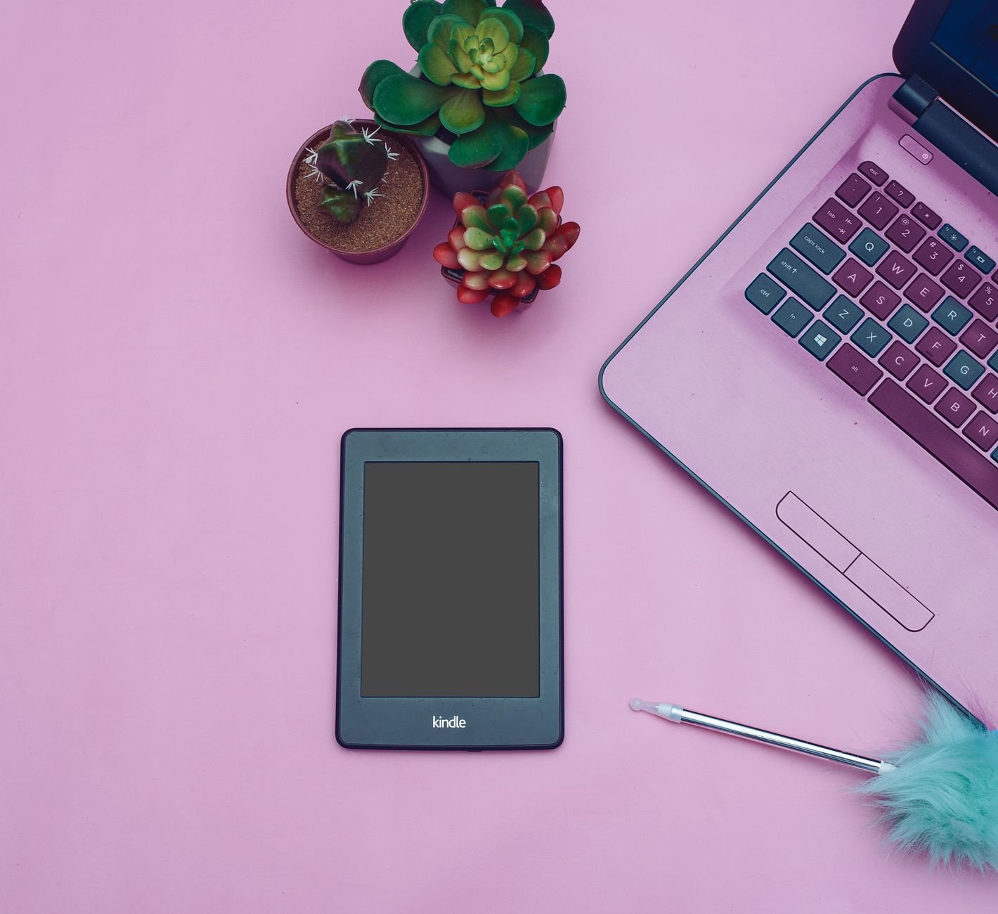 Flat lay of a digital product on a warm desk — an ebook on a Kindle beside a laptop